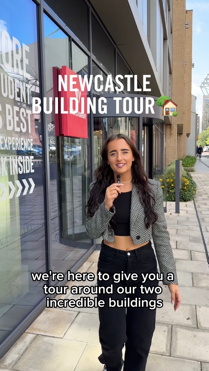 A person is standing outside a building with modern glass windows, holding a microphone. Text on the image reads "Newcastle Building Tour" and mentions a tour of two buildings.