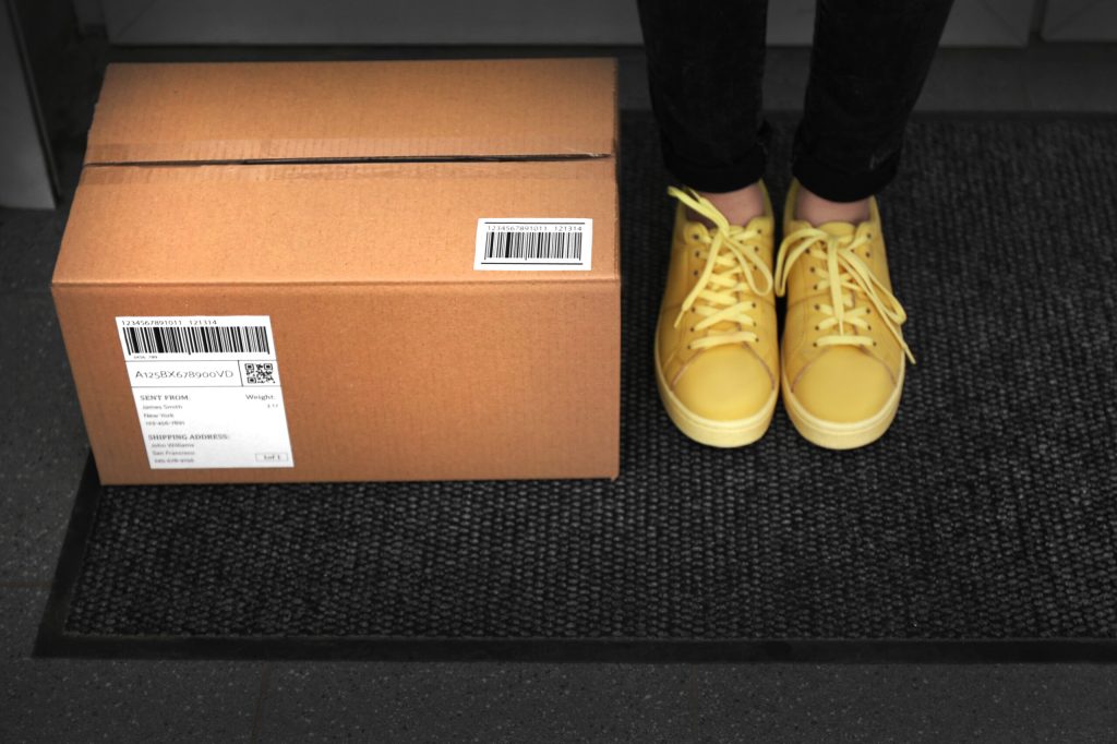 A person wearing yellow shoes standing next to a box.